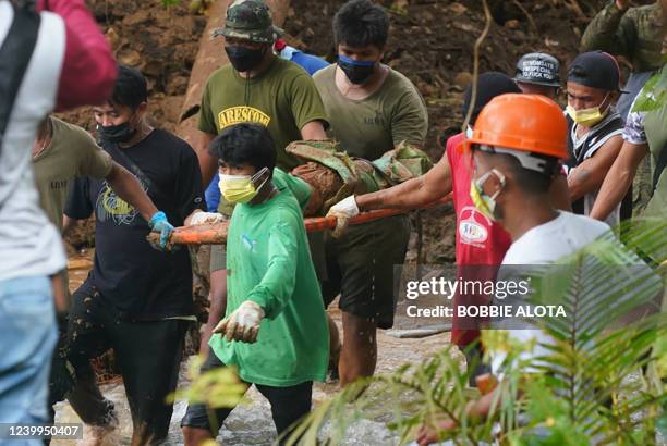 Rescue workers carry a retrieved body of one of the victims of the landslide that slammed the village of Bunga in Baybay town, Leyte province on...