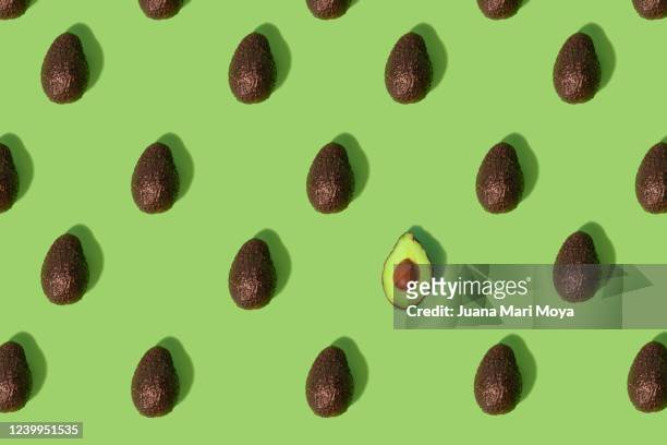 concept stand out from the crowd  large group of whole avocados placed in a repeating pattern where one split in half stands out from the crowd - dipset stockfoto's en -beelden