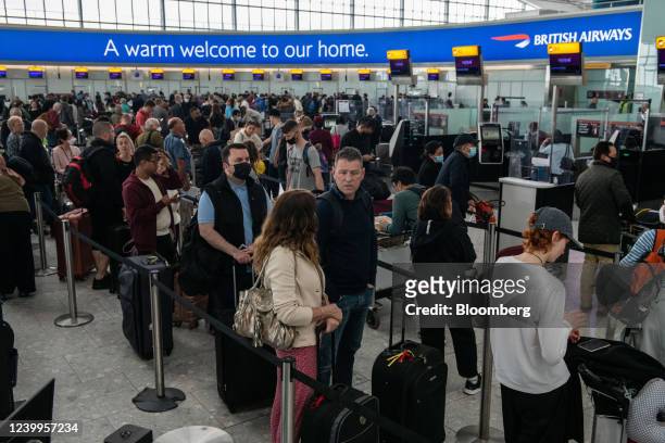 Passengers queue to check in at British Airways desks inside the departures hall of Terminal 5 at London Heathrow Airport in London, U.K., on...