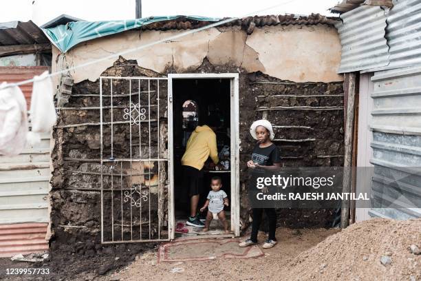 Residents stand at their damaged home in Bhambayi township following, heavy rains, mudslides and winds, in Durban, on April 13, 2022. - Devastating...