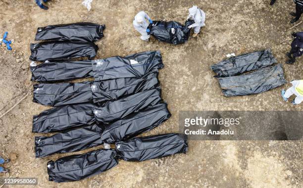 An aerial view of officials continue to exhume the bodies of civilians who died during the Russian attacks, from second mass grave, found at backyard...