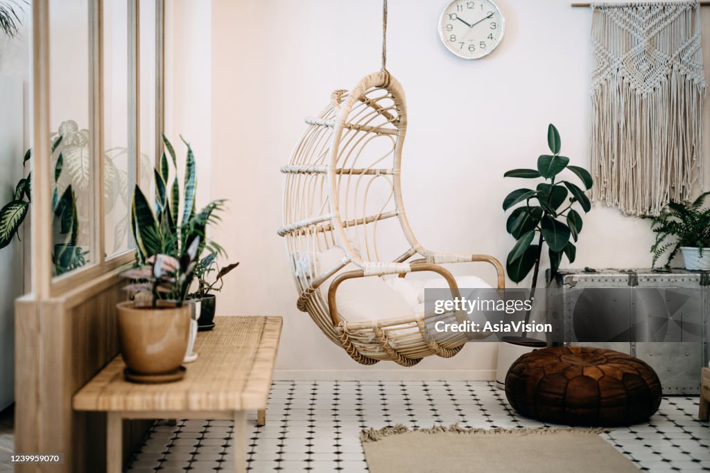 Cadeira aconchegante pendurada na sala de estar loft com design elegante e bohemia. Bem projetado e decorado com uma variedade de plantas interessantes