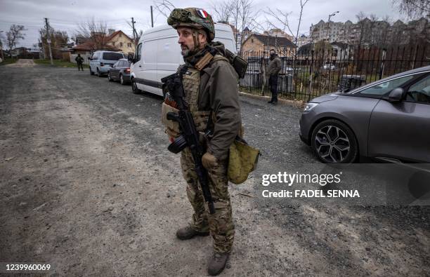 Graphic content / A soldier wearing a French insigna accompanying French gendarmerie forensic investigators stands on the road in Bucha, on the...