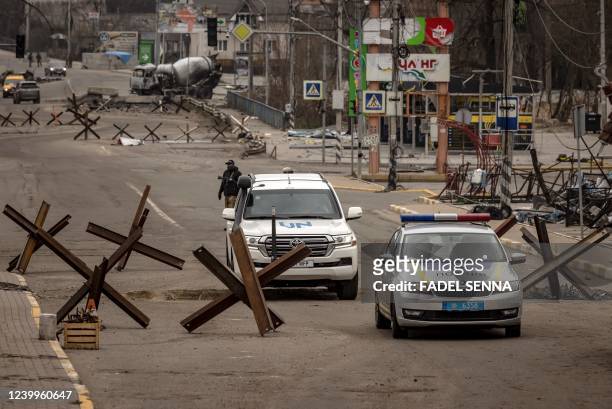 Graphic content / A UN and a police car ride in Bucha, on the outskirts of Kyiv, on April 13 amid Russia's military invasion launched on Ukraine. - A...