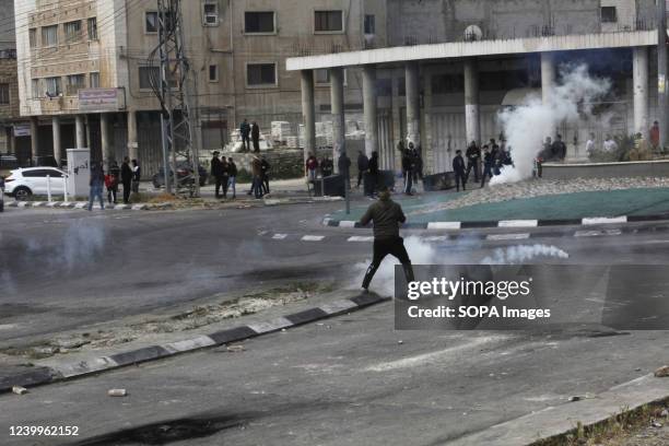 Palestinians flee from tear gas canisters fired by the Israeli army while protecting Jewish settlers as they repair Joseph's Tomb after it was...