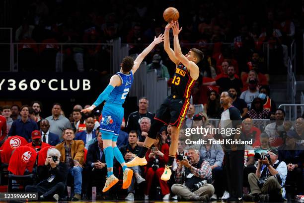 Bogdan Bogdanovic of the Atlanta Hawks shoots a three-point shot over LaMelo Ball of the Charlotte Hornets during the first half at State Farm Arena...