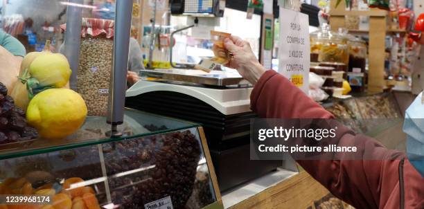 April 2022, Spain, Palma: A customer pays for the purchase at the Pere Garau market in Palma. After the rise in inflation and the shortage of food...