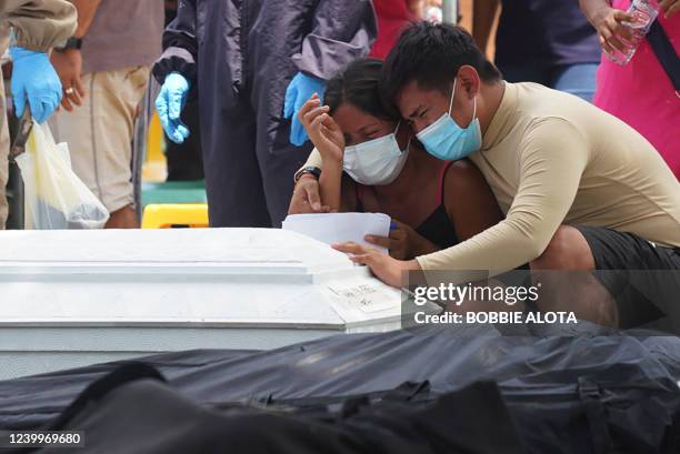 Residents cry in front of a coffin and a body bag as they mourn for their dead relatives, victims of a landlside that slammed Pilar village in Abuyog...