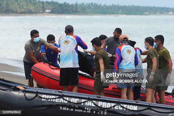 Rescue workers unload from an inflatable boat a body bag containing resident's dead body, victim of a landlside that slammed Pilar village in Abuyog...
