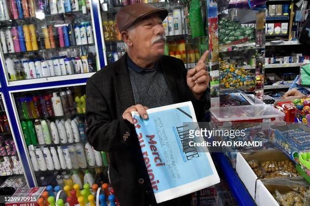French-language daily newspaper vendor holds the final issue of Algerian French-language daily newspaper "Liberté" at a stand in Algeria's capital...