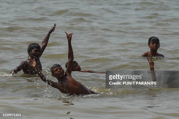 Children play in the Arabian sea during a hot afternoon in Mumbai on April 14, 2022.