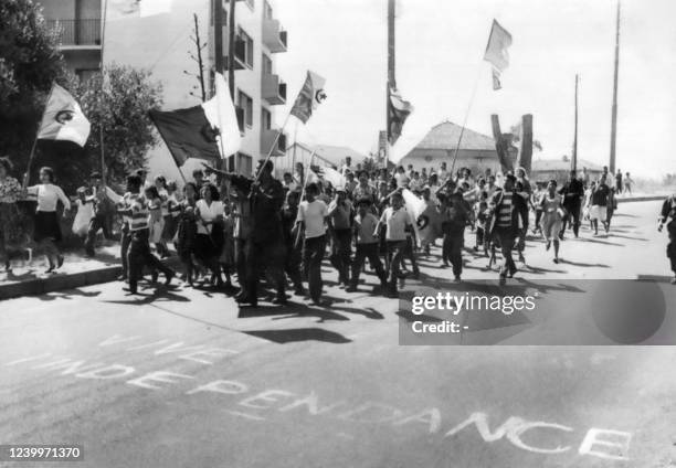 Young Algerians marching between the European and Muslim quarters of Algiers, waving Algerian flags, celebrate independence of Algeria on July 2,...