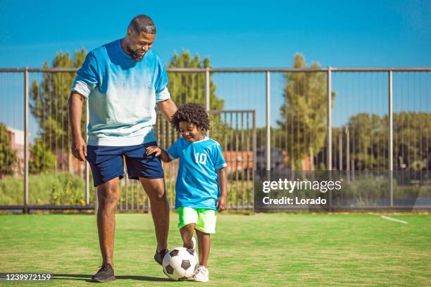 padre negro y joven hijo entrenando en el campo de fútbol - football training fotografías e imágenes de stock