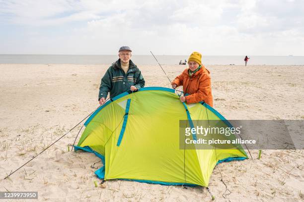 April 2022, Lower Saxony, Schillig: Vacationers Friedhelm and Magdalena Isenberg from North Rhine-Westphalia set up their beach shell on Schilling's...