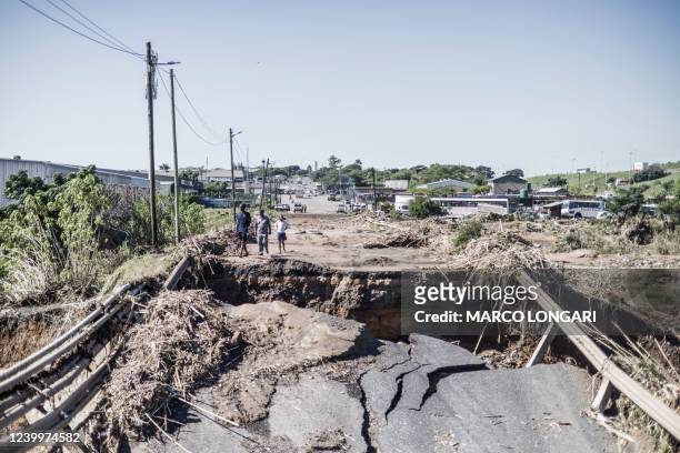 Residents stand on a collapsed bridge north of Durban, on April 14, 2022. - Victims of South Africa's worst flooding on record clamoured for relief...