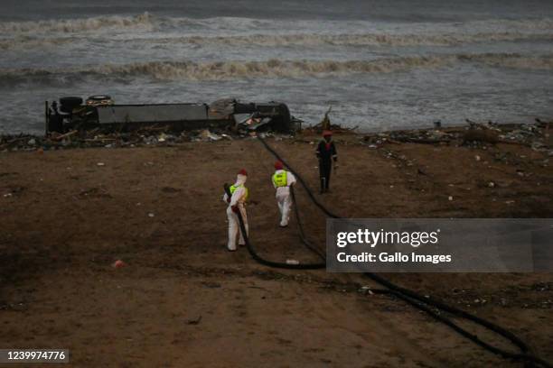 Spill Tech cleaning up a road tanker washed up on a Durban beach amid floods and heavy rain on April 12, 2022 in Durban, South Africa. According to...