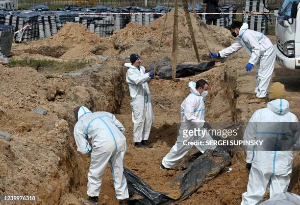 Workers exhume bodies from a mass grave in Bucha, north-west of Kyiv, on April 14, 2022. - French gendarmes and forensic doctors have arrived in...