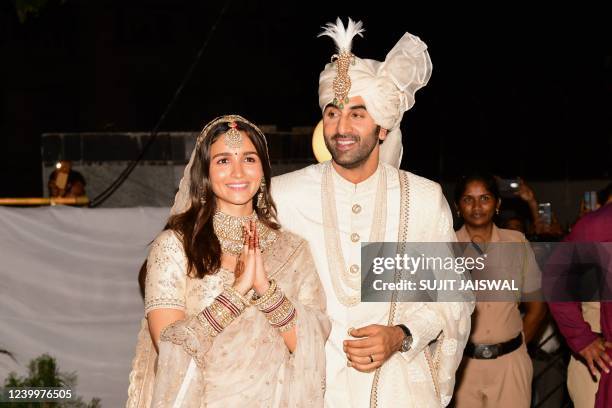 Bollywood actors Ranbir Kapoor and Alia Bhatt gesture as they pose for pictures during their wedding ceremony in Mumbai on April 14, 2022.