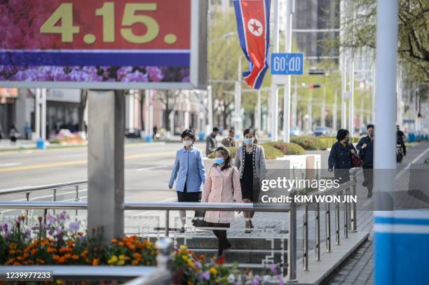 Pedestrians walk near a poster displayed to celebrate the 110th birth anniversary of the late North Korean leader Kim II Sung, known as the 'Day of...