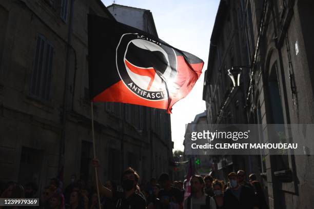 Protester waves the anti-fascist movement flag "Action antifasciste" during a rally against the French far-right party Rassemblement National...