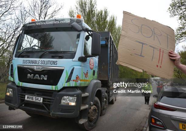 Protesters hold up placards to trucks as they leave the landfill site on April 14, 2022 in Newcastle-Under-Lyme, England. Stop the Stink have been...