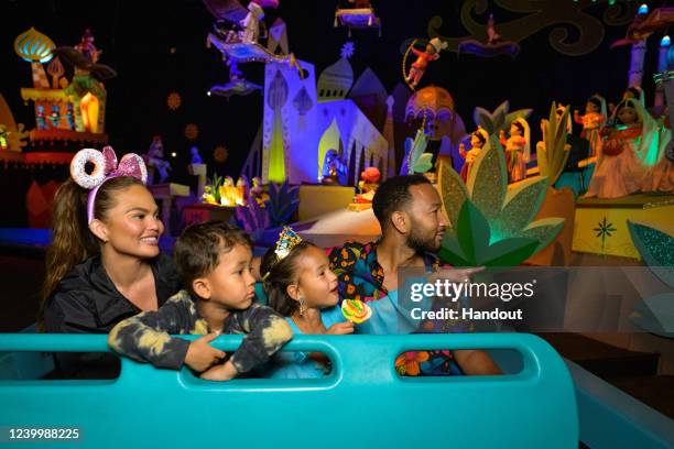 In this handout photo provided by Disneyland Resort, Chrissy Teigen, John Legend and their children, Miles and Luna, ride on ‘It's A Small World’ at...