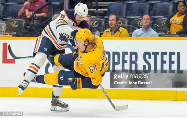 Kris Russell of the Edmonton Oilers hits Mikael Granlund of the Nashville Predators during an NHL game at Bridgestone Arena on April 14, 2022 in...