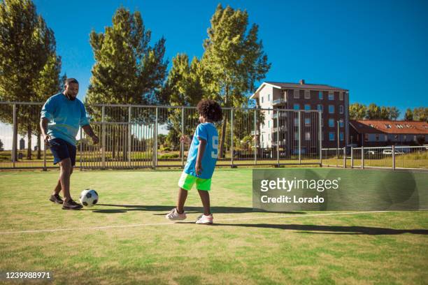père noir et jeune fils s’entraînant sur le terrain de football - father son challenge round two photos et images de collection