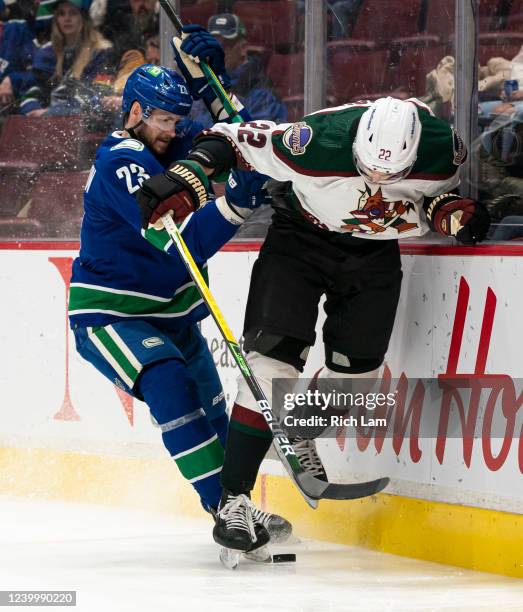 Oliver Ekman-Larsson of the Vancouver Canucks checks Jack McBain of the Phoenix Coyotes along the end boards during the first period at Rogers Arena...