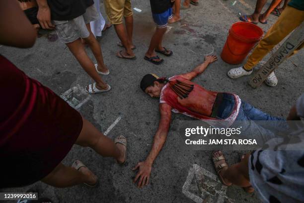 Catholic devotee lies on the ground while flagellating himself to mark the holy week of Easter in Navotas, suburban Manila on April 15, 2022.