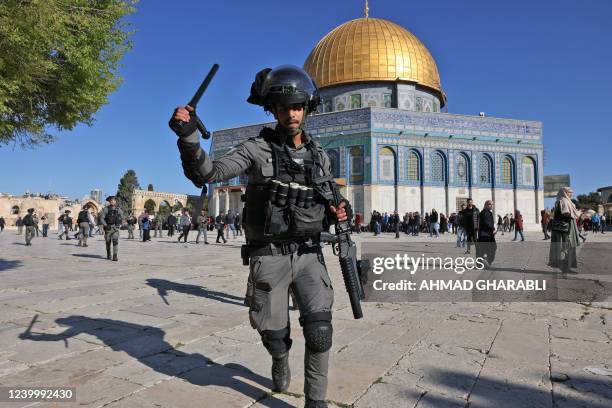 Member of the Israeli security forces lifts his batton in front of the Dome of the Rock mosque during clashes at Jerusalem's Al-Aqsa mosque compound,...