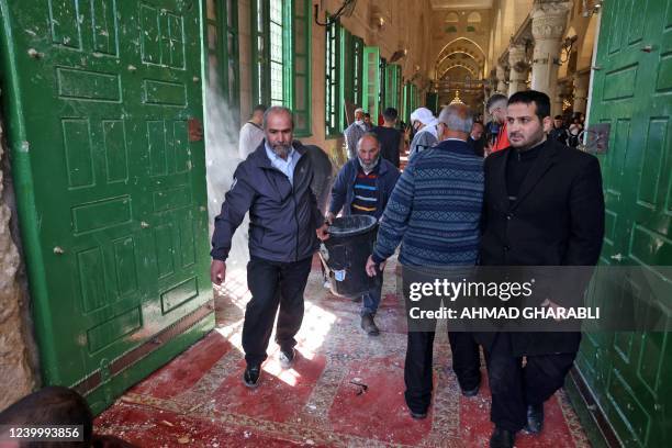 Muslim worshippers clean-up debris following clashes between Palestinian demonstrators and Israeli police at Jerusalem's Al-Aqsa mosque complex, on...