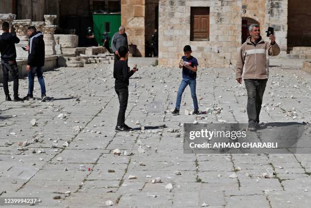 Muslim worshippers take pictures of debris following clashes between Palestinian demonstrators and Israeli police at Jerusalem's Al-Aqsa mosque...