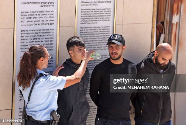 An Israeli police officer gives a drink of water to one of the Palestinian youths who took part in a protest at the al-Aqsa mosque compound, after...