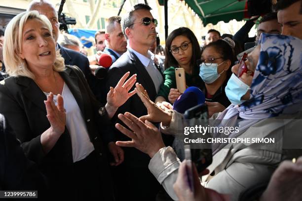 French far-right party Rassemblement National presidential candidate Marine Le Pen gestures as she speaks with a woman during a campaign visit at...