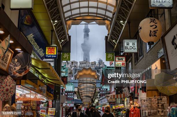 The Tokyo Skytree tower is seen as people walk along a shopping street near Sensoji Temple in Tokyo on April 15, 2022.