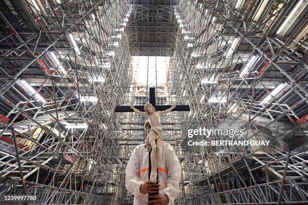 Catholic faithful holds a crucifix during a Good Friday Meditation prayer carried out by prelates in the Notre-Dame cathedral in Paris on April 15...