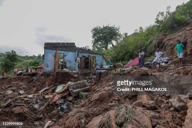 Neighbours stand next to the remains of a house at KwaNdengezi township outside Durban on April 15, 2022 where ten people are reported to be missing...