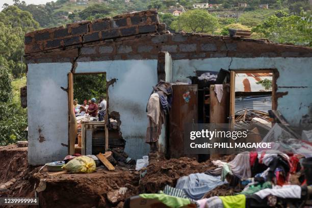 Neighbours stand next to the remains of a house at KwaNdengezi township outside Durban on April 15, 2022 where ten people are reportedly missing...