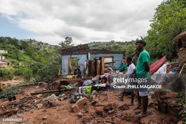 Neighbours stand next to the remains of a house at KwaNdengezi township outside Durban on April 15, 2022 where ten people are reportedly missing...