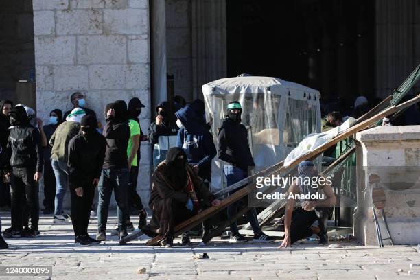 Palestinians throw stones in response to Israeli forces' intervention after they react to the Israeli raid at Al-Aqsa Mosque in Jerusalem on April...