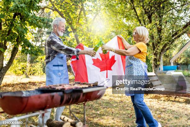 senior couple making barbecue together in their garden. - canada day party stock pictures, royalty-free photos & images