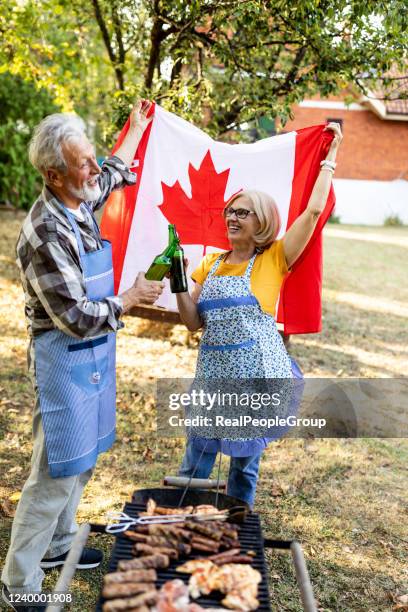 senior couple making barbecue together in their garden. - canada day party stock pictures, royalty-free photos & images