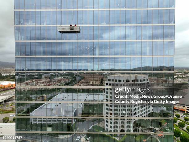 Irvine, CA Window washers work on the upper floors of 400 Spectrum Center as buildings are reflected in the lower portion of the 20-story tower in...