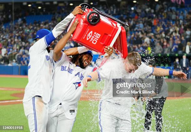 Zack Collins of the Toronto Blue Jays gets water dumped on him by teammates Vladimir Guerrero Jr. #27 and Lourdes Gurriel Jr. #13 after their team...