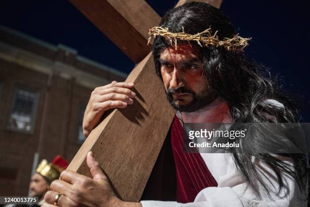 Elias Hernandez playing Jesus, carries a large wooded cross through the streets of the city as he is taunted and fake whipped by actors playing Roman...