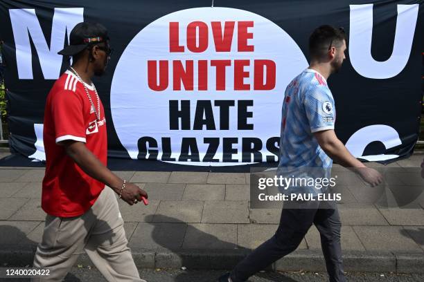 Supporters walk past a banner displaying an anti-Glazer message outside Manchester United's Old Trafford stadium in Manchester, north west England on...