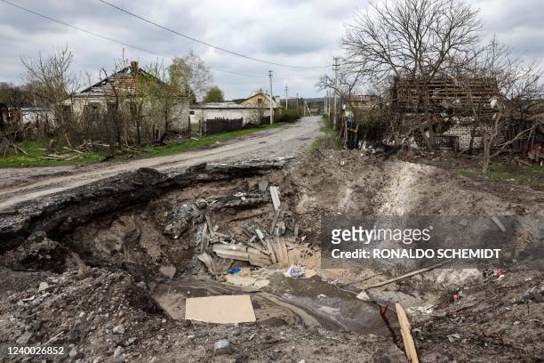 Crater and a destroyed home are pictured in the village of Yatskivka, eastern Ukraine on April 16, 2022. - Russia's military focus now seems to be on...
