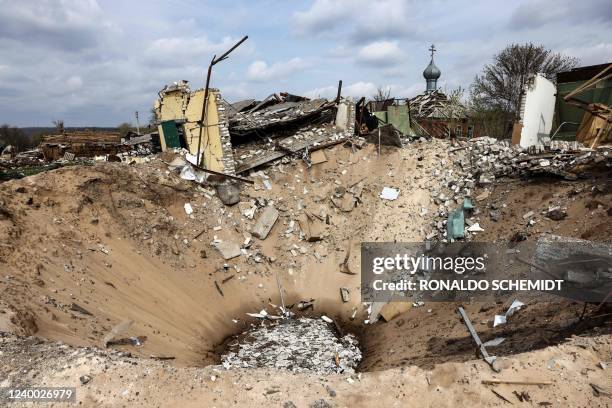 Crater and a destroyed home are pictured in the village of Yatskivka, eastern Ukraine on April 16, 2022. - Russia's military focus now seems to be on...