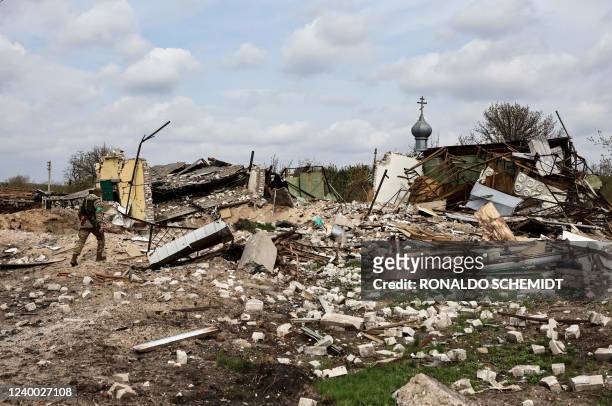 Ukranian serviceman walks towards a destroyed house in the village of Yatskivka, eastern Ukraine on April 16, 2022. - Russia's military focus now...